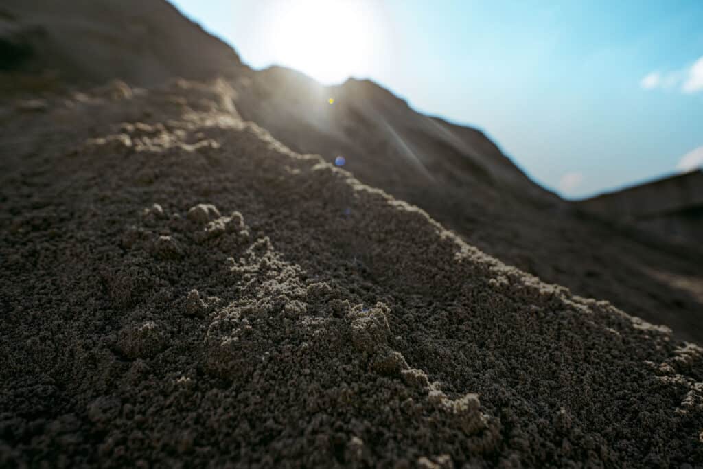 Nahaufnahme der dunklen Sand- und Kiesstruktur. Sand und Kies.