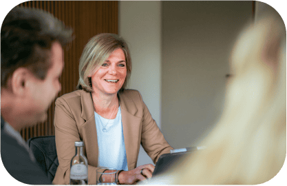 Lächelnde Geschäftsfrau in einem beigen Blazer nimmt an einem Meeting teil.