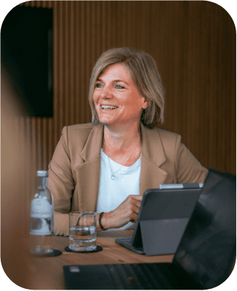 Lächelnde Geschäftsfrau, die an ihrem Schreibtisch mit Laptop und Tablet arbeitet.