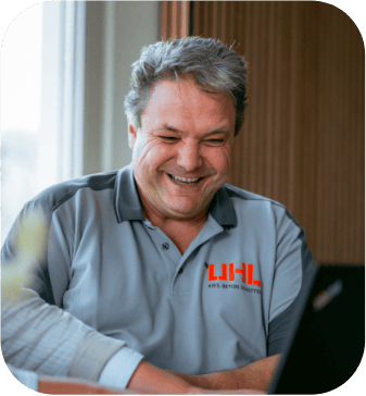 Glücklicher Mann im UHL-Arbeitspoloshirt mit Laptop