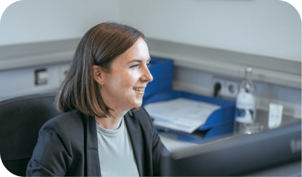 Lächelnde Geschäftsfrau an ihrem Schreibtisch, die Dokumente durchsieht.