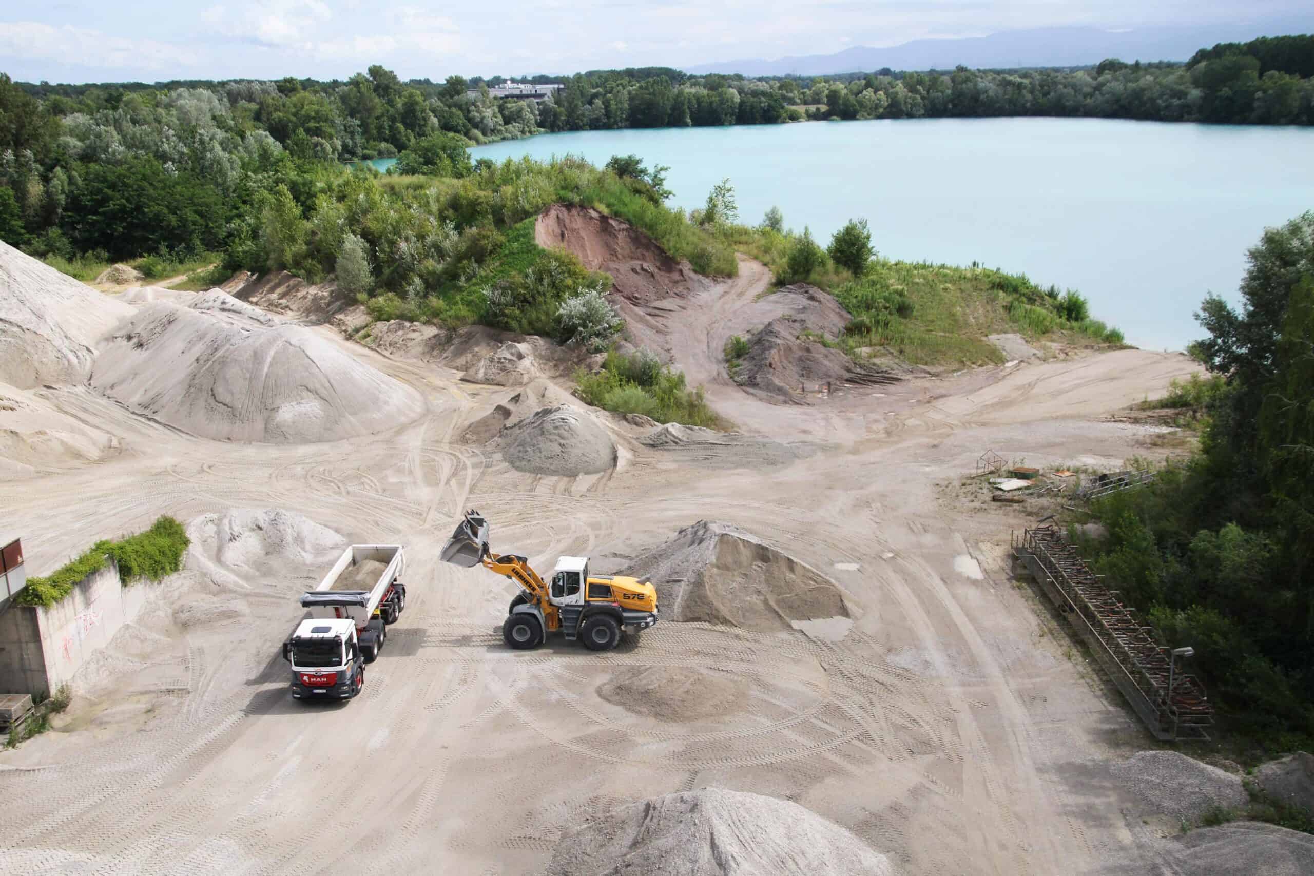 Radlader lädt in einem Steinbruch Sand in einen Muldenkipper.