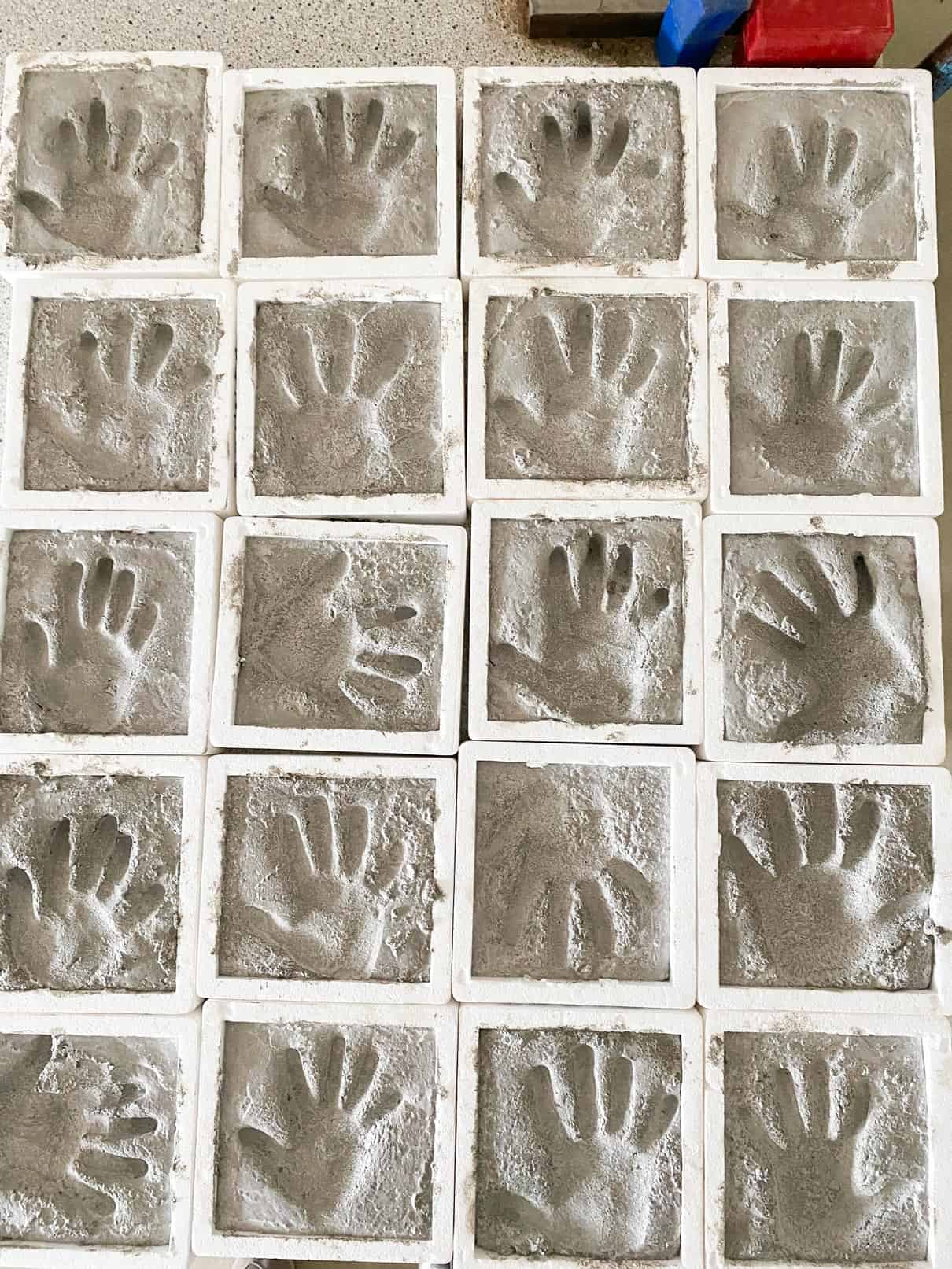 Raster aus konkreten Handabdrücken, jeweils in einem weißen quadratischen Rahmen.