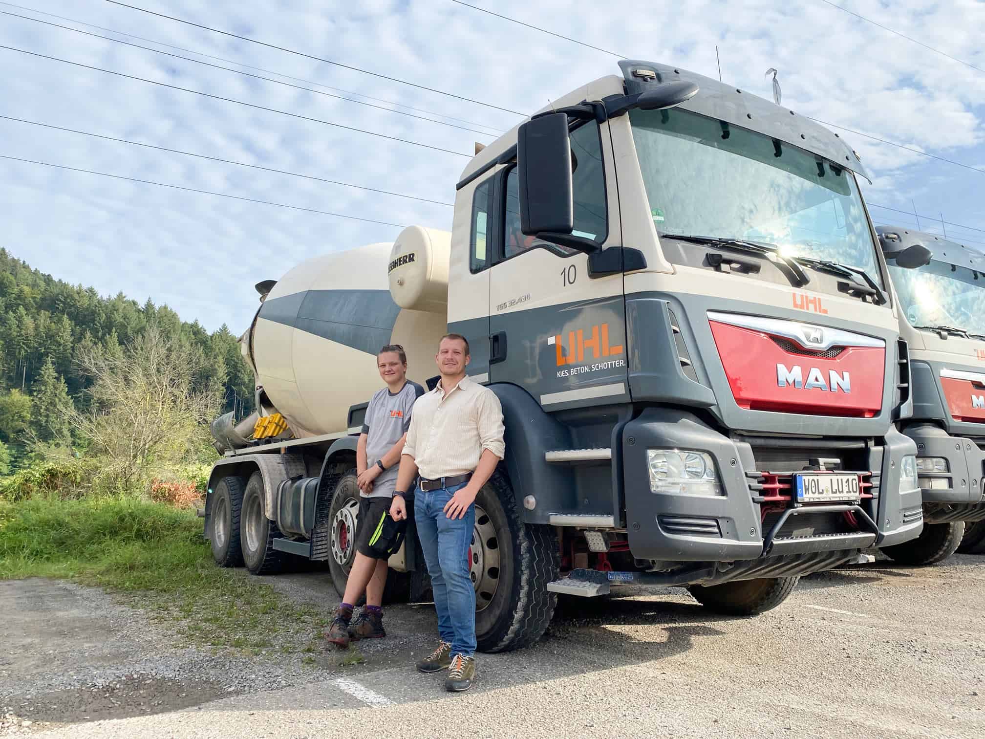 Zwei Männer stehen stolz neben einem LHL-Betonmischer.