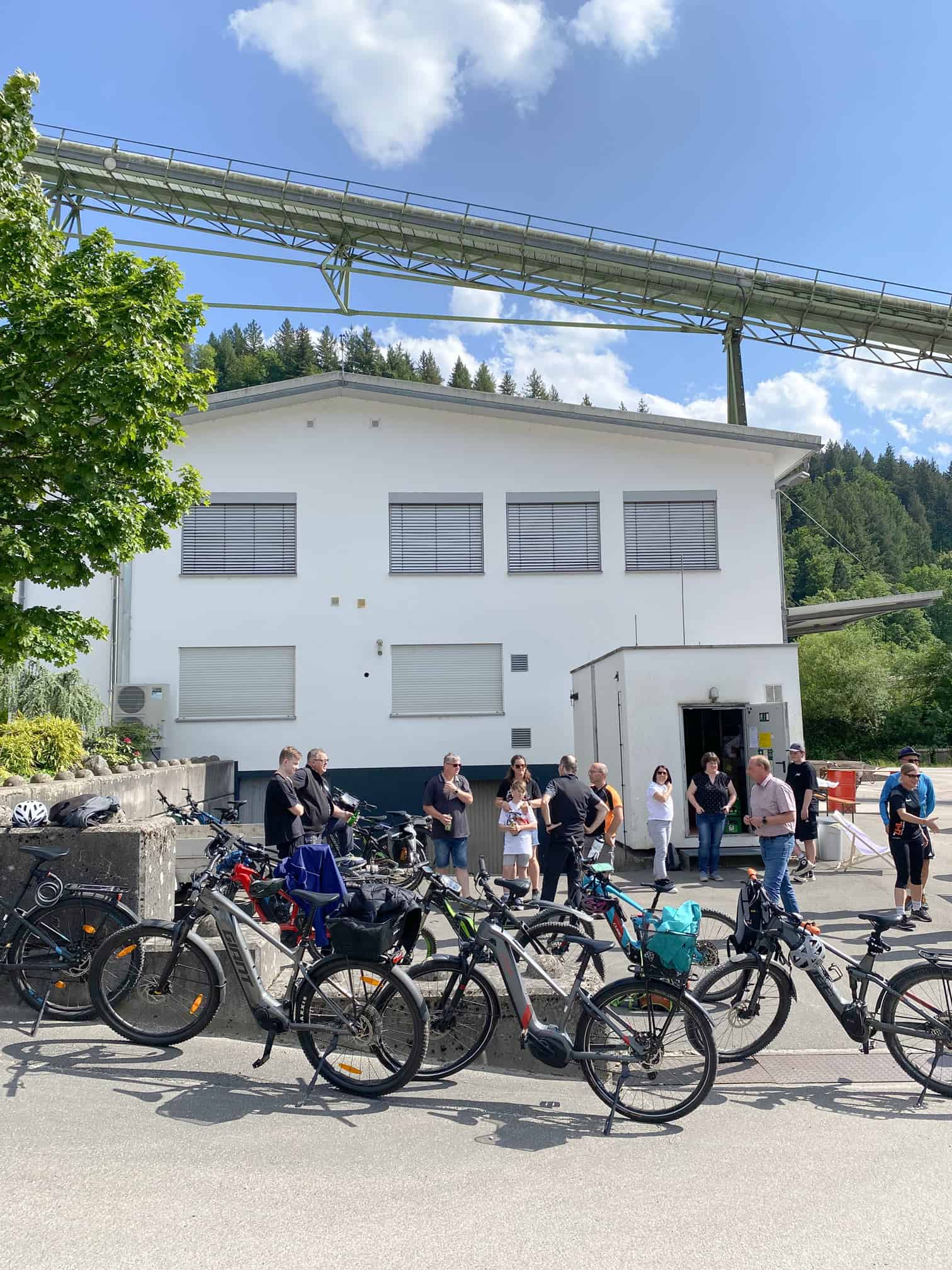 Gruppe von Menschen mit E-Bikes, die vor einem weißen Gebäude geparkt sind