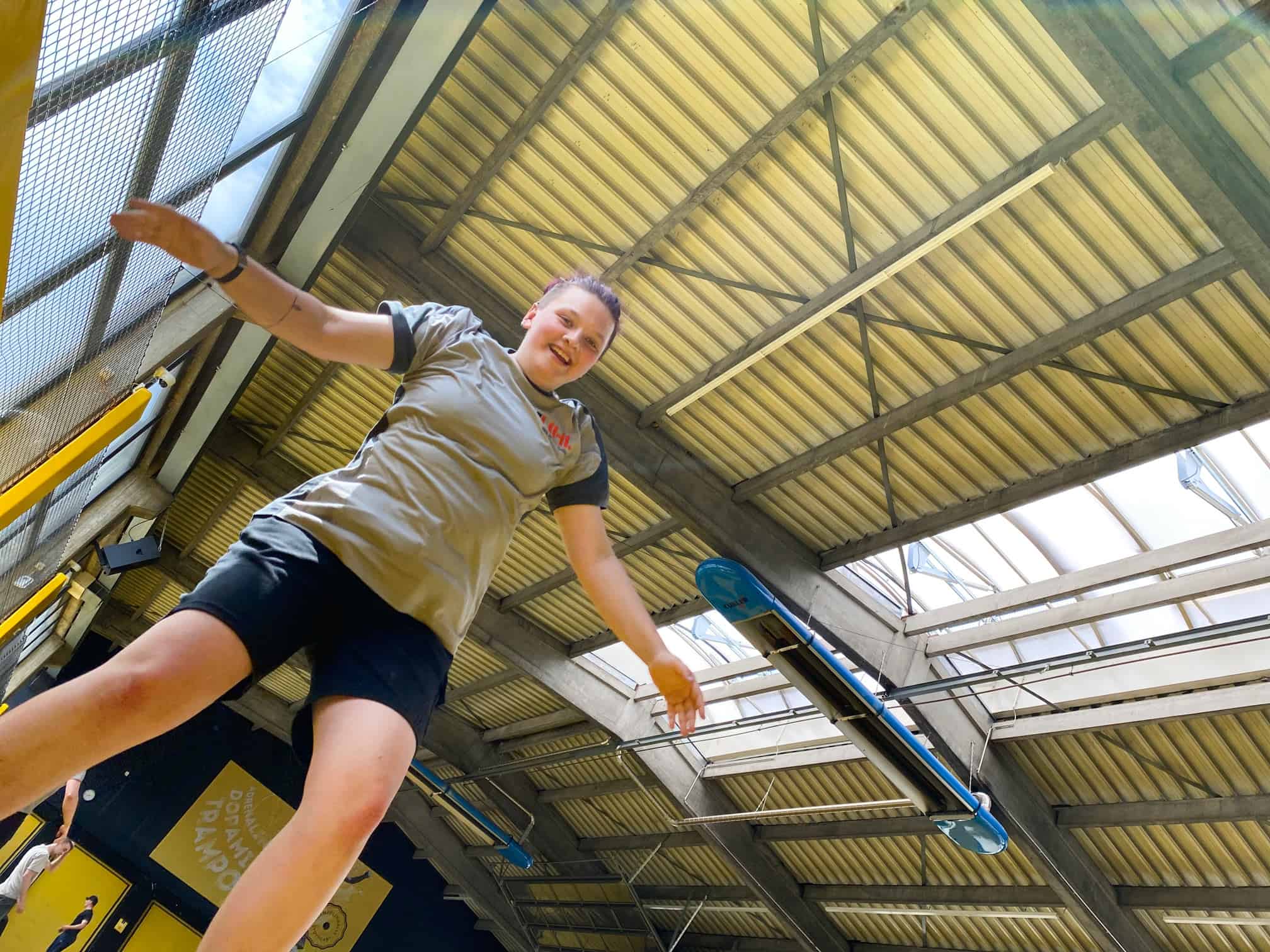 Junge Frau balanciert auf einem niedrigen Balken hoch oben in einem Trampolinpark.