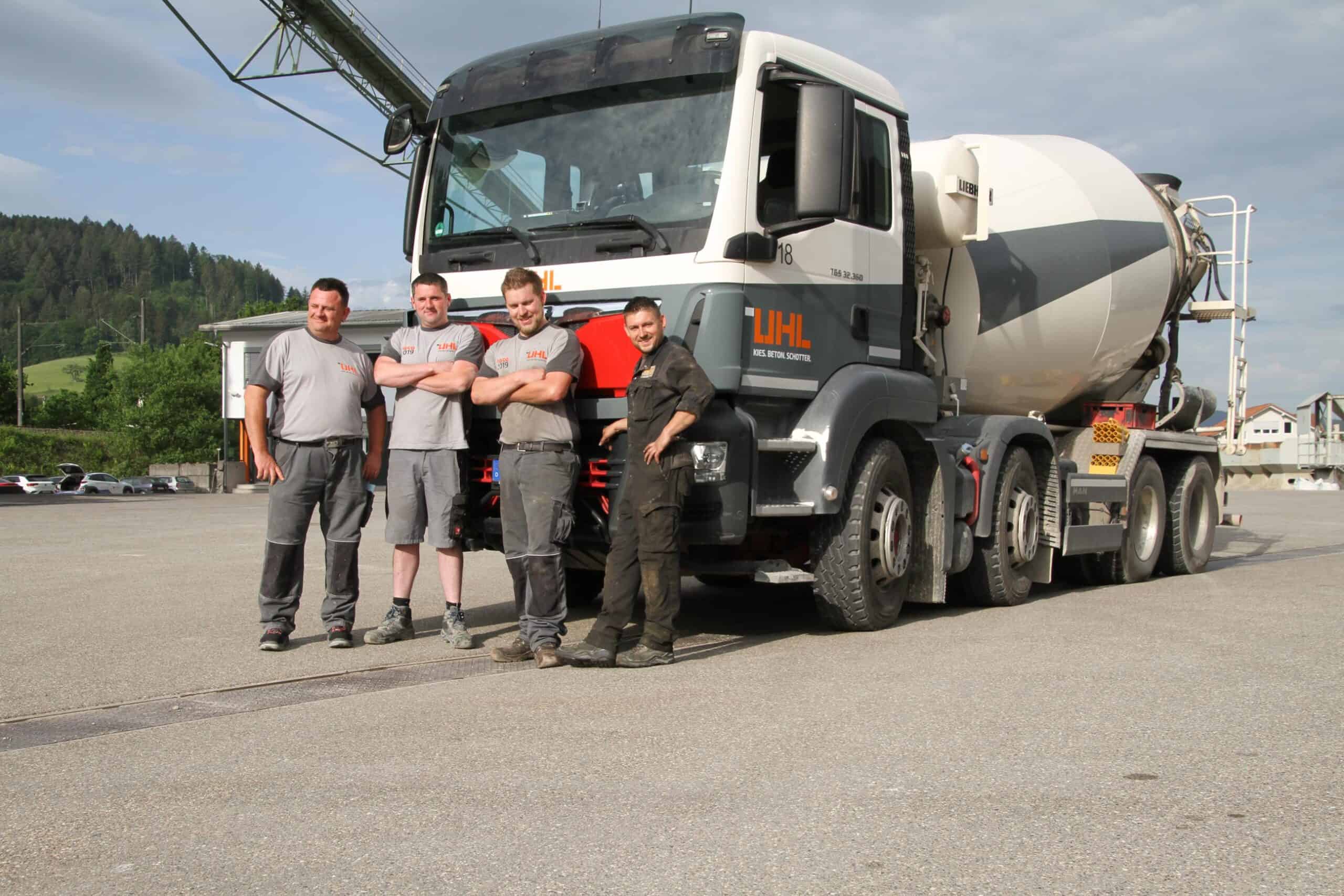 Vier Arbeiter stehen stolz neben ihrem Betonmischer-LKW und präsentieren ihre Betondienstleistungen.