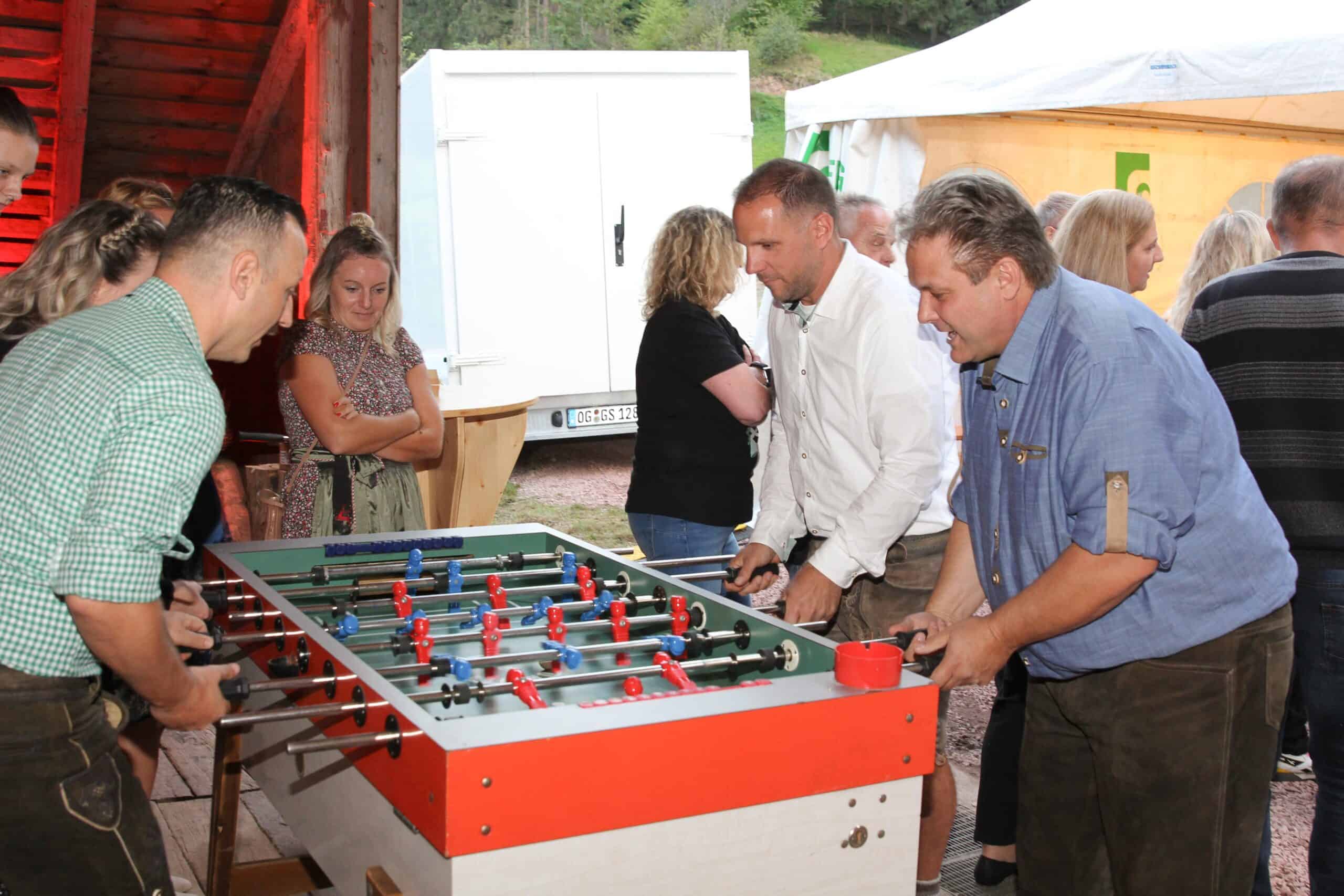 Leute, die bei einer Firmenveranstaltung Tischfußball spielen.